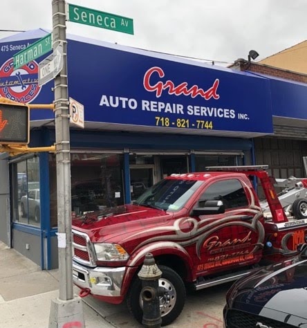 The exterior of Grand Auto Repair show with street signs in front showing the corner of Seneca Ave and Harmon St